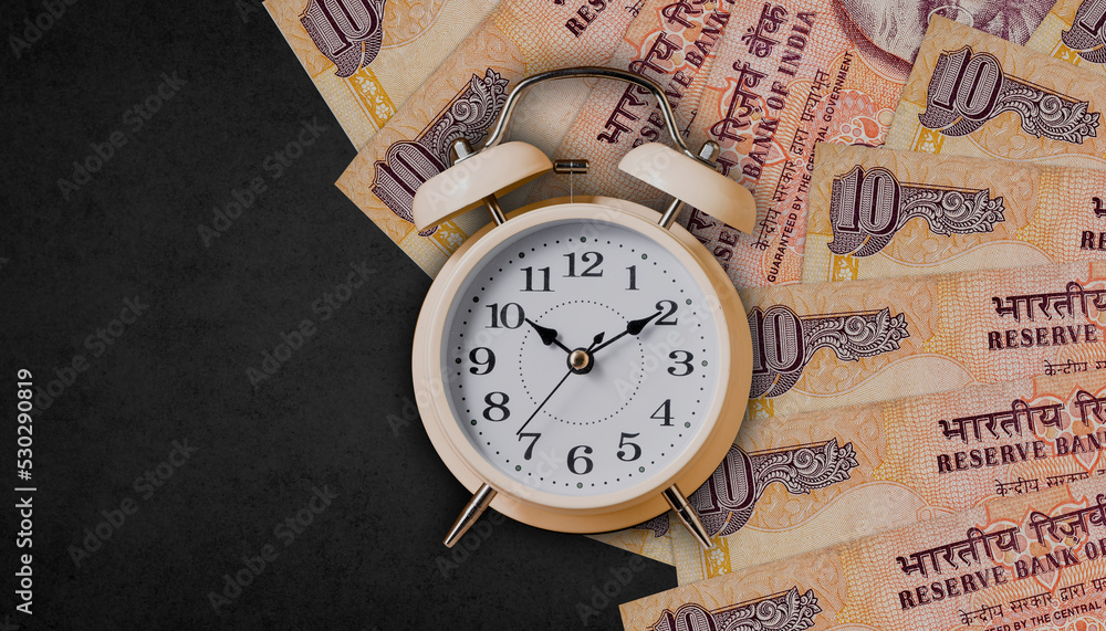 Alarm clock on indian ten rupees notes on black background, time to invest,, loan, business and insurance idea Alarm clock on indian ten rupees notes on black background, time to invest,, loan, business and insurance idea