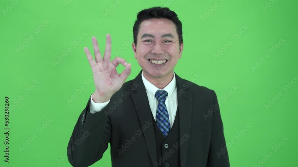 Asian businessman showing the OK - Okay hand sign on chroma green screen. Asian businessman showing the OK - Okay hand sign on chroma green screen.