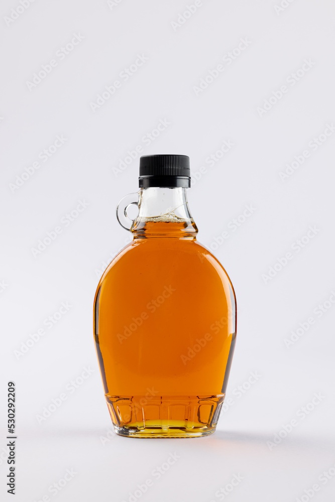 Vertical image of glass bottle of maple syrup on white background, with copy space Vertical image of glass bottle of maple syrup on white background, with copy space