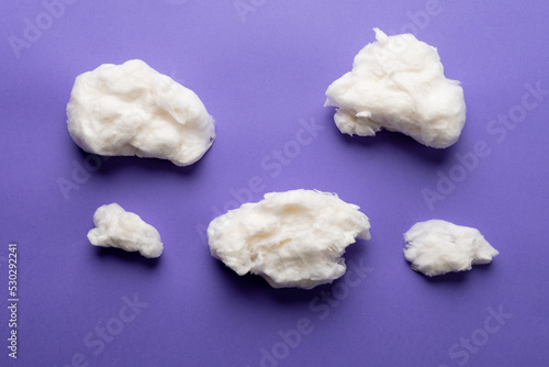 Horizontal image of tufts of homemade white candy floss, on purple background
