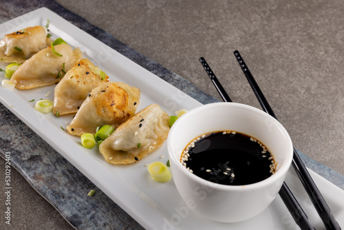 Close up of dumplings, soy sauce and chopsticks on grey background