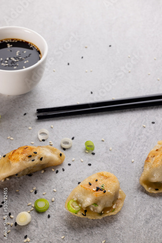 Close up of asian dumplings, soy sauce and chopsticks on grey background