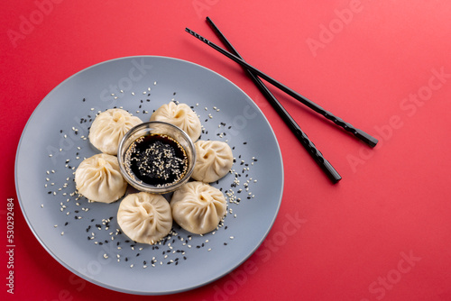 Overhead view of asian dumplings, soy sauce and chopsticks on red background
