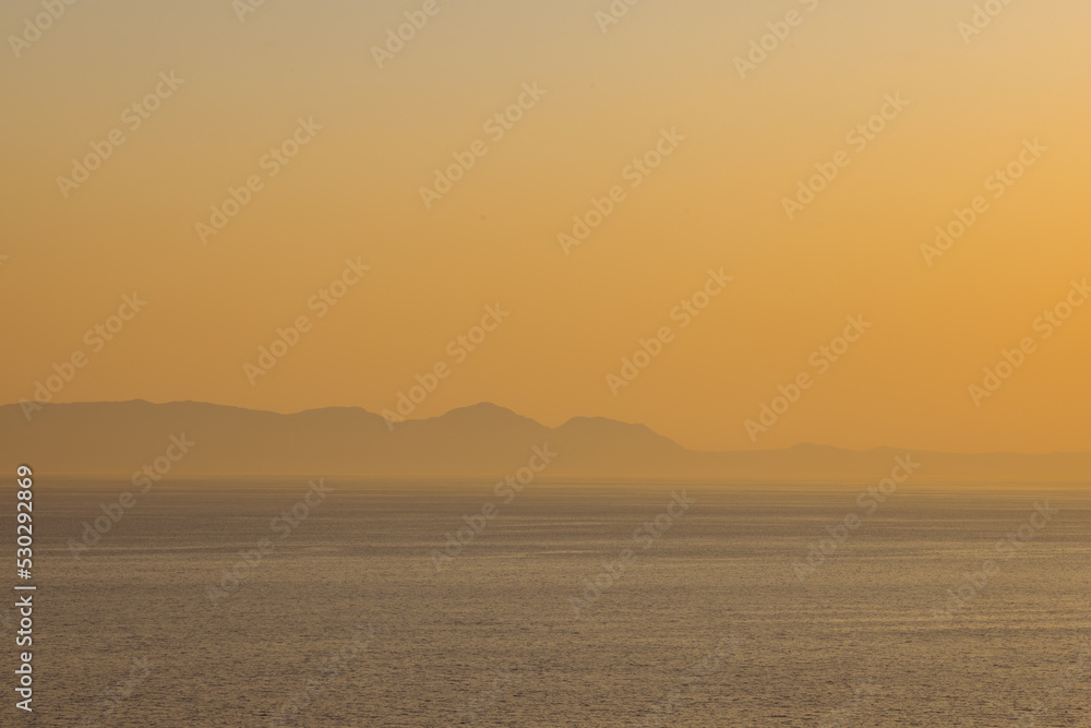 Landscape of sea, sea shore with mountains, cloudless sky at sunset and horizon