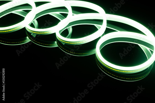 Image of vibrant spiral green neon glow sticks over black background with copy space