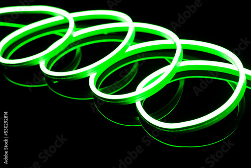 Image of vibrant spiral green neon glow sticks over black background with copy space