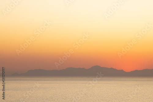 Landscape of sea  sea shore with mountains  cloudless sky at sunset and horizon