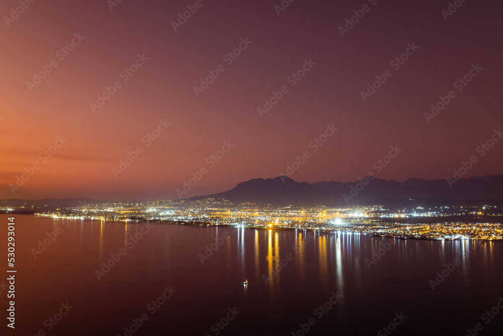 Composition of landscape of mountains and sea with cityscape