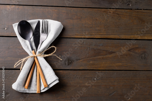Overhead view of cutlery, rustic string and napkin with copy space on wooden background