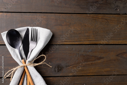 Overhead view of cutlery, rustic string and napkin with copy space on wooden background