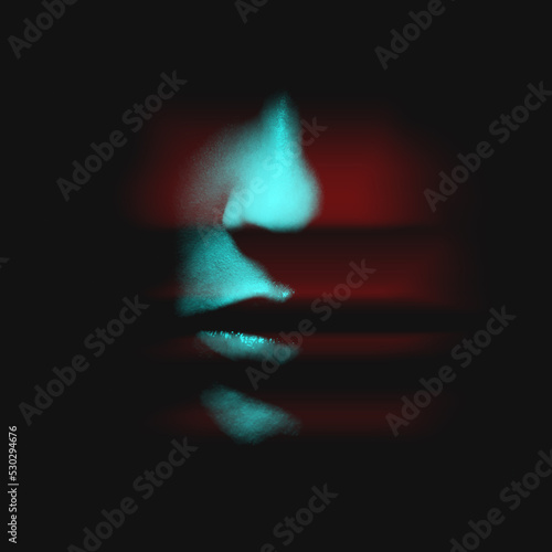 Abstract fashion concept. Woman face in black shadow background with copy space in red and blue color split effect style. Nose is in camera focus. Selective focus and image with shallow depth of field