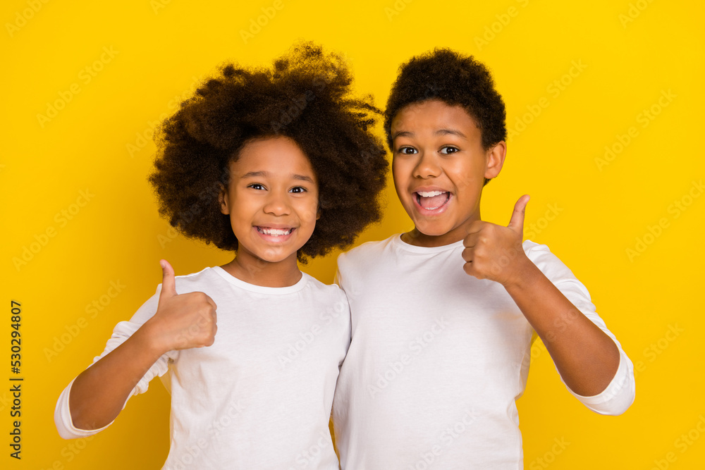 Photo of two little buddies hand finger demonstrate thumb up feedback rate isolated on yellow color background Photo of two little buddies hand finger demonstrate thumb up feedback rate isolated on yellow color background