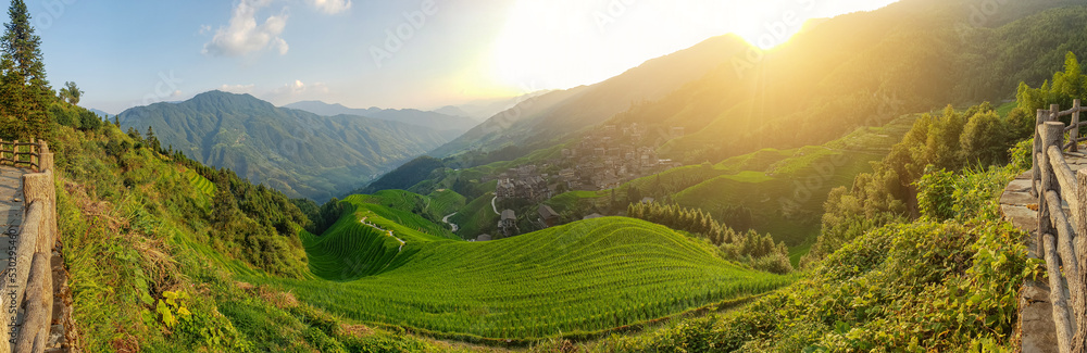 A magical photo of a mountain landscape at sunset. A village on the slopes. Winding roads. Terraced fields. China.