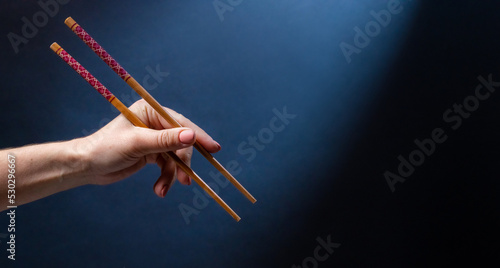Hand holding japanese chopstick for sushi maki food. Traditional bamboo tool for oriental cuisine