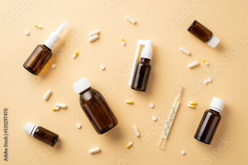 Seasonal diseases concept. Top view photo of medicines spray and syrup transparent brown bottles pills capsules and thermometer on isolated beige background