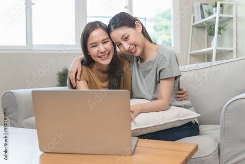 two happy women lesbian couple watching series on internet via touchpad relax together. © Pormezz