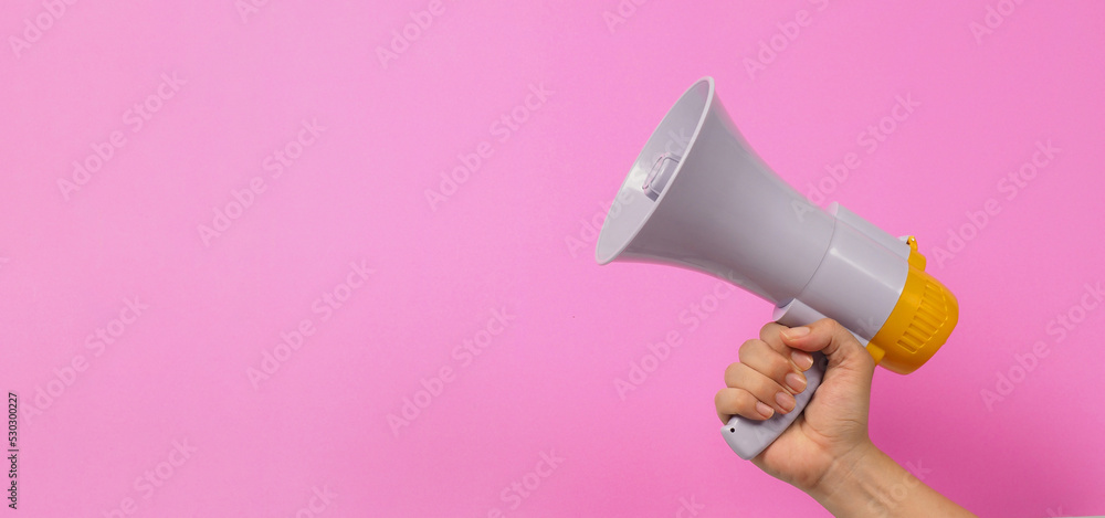 Hand is hold megaphone on pink background.. - obrazy, fototapety, plakaty 