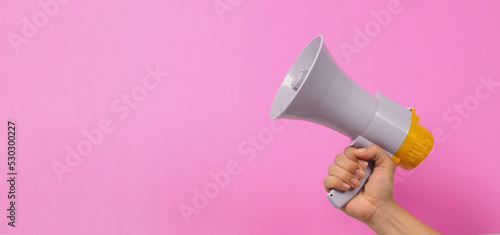 Hand is hold megaphone on pink background.. photo