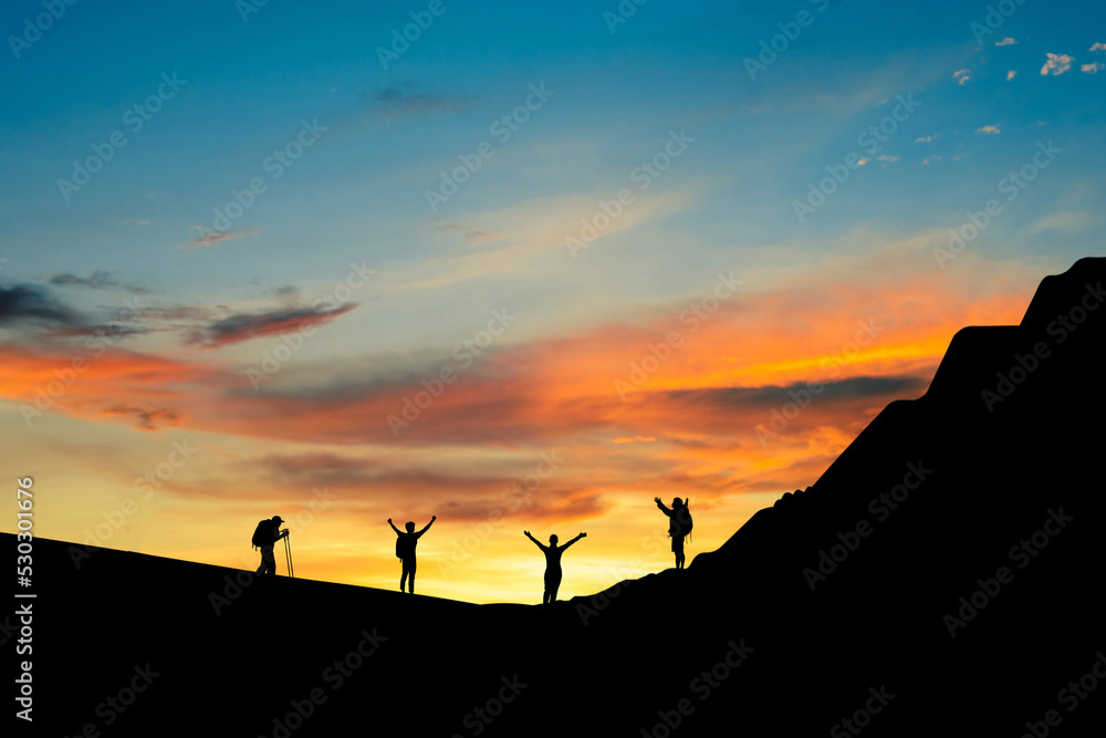 Silhouette of small group young traveler standing open arms on top of the mountain in the morning. They was delighted and happy to come and see the sunrise from the top of the mountain.