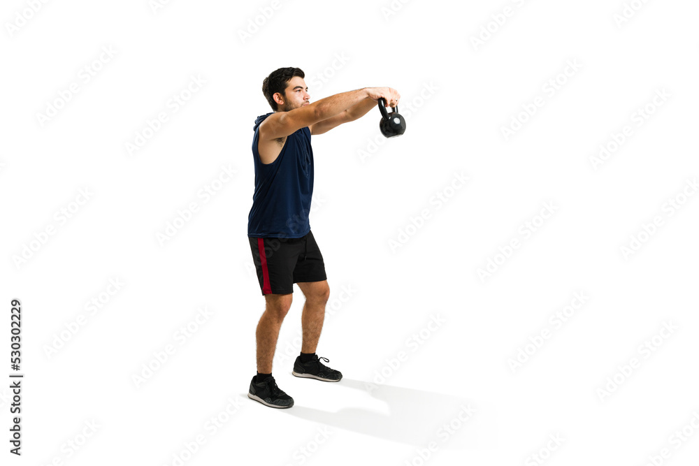 Full length of a fit man exercising with a kettlebell weight Full length of a fit man exercising with a kettlebell weight