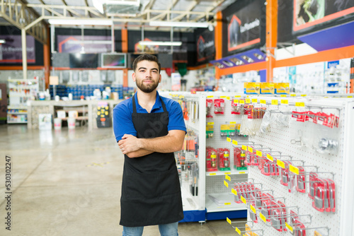 Obraz na plátně Portrait of a young man and hardware store worker looking at the camera