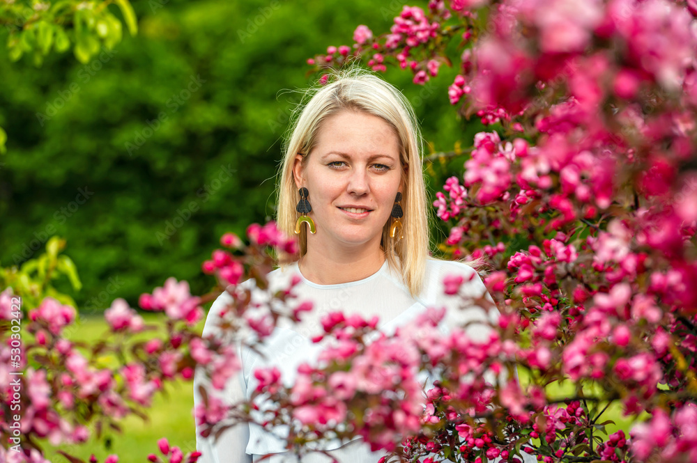 closeup portrait of a smiling blonde woman in a blossoming garden in spring, selective focus closeup portrait of a smiling blonde woman in a blossoming garden in spring, selective focus
