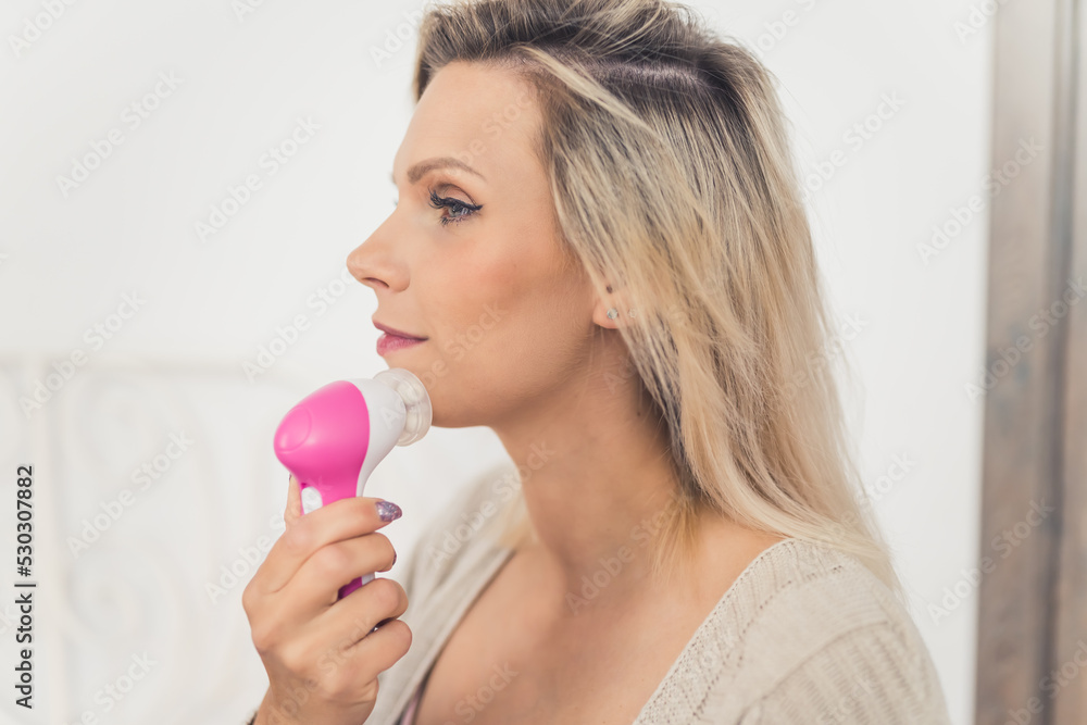 Beautiful caucasian young woman using an electric facial skin anti-aging massager and cleaner in the morning. High quality photo Beautiful caucasian young woman using an electric facial skin anti-aging massager and cleaner in the morning. High quality photo