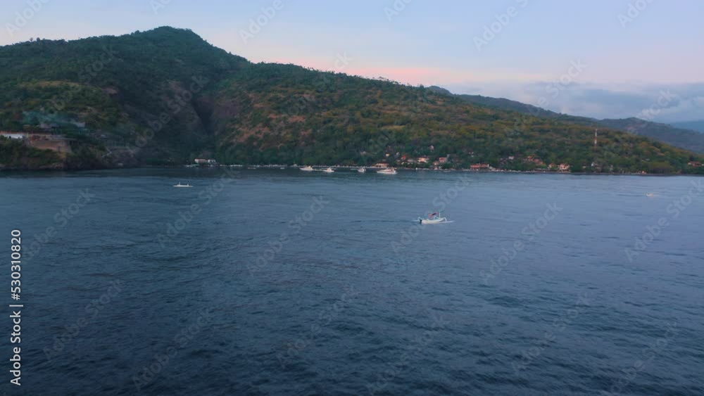 Peaceful sunrise landscape with a distant mountain color blue pink and two white motorboat on sea surface. Amazing dawn at seaside aerial copter view. Drone flying above a two vessels on calm ocean. Peaceful sunrise landscape with a distant mountain color blue pink and two white motorboat on sea surface. Amazing dawn at seaside aerial copter view. Drone flying above a two vessels on calm ocean.