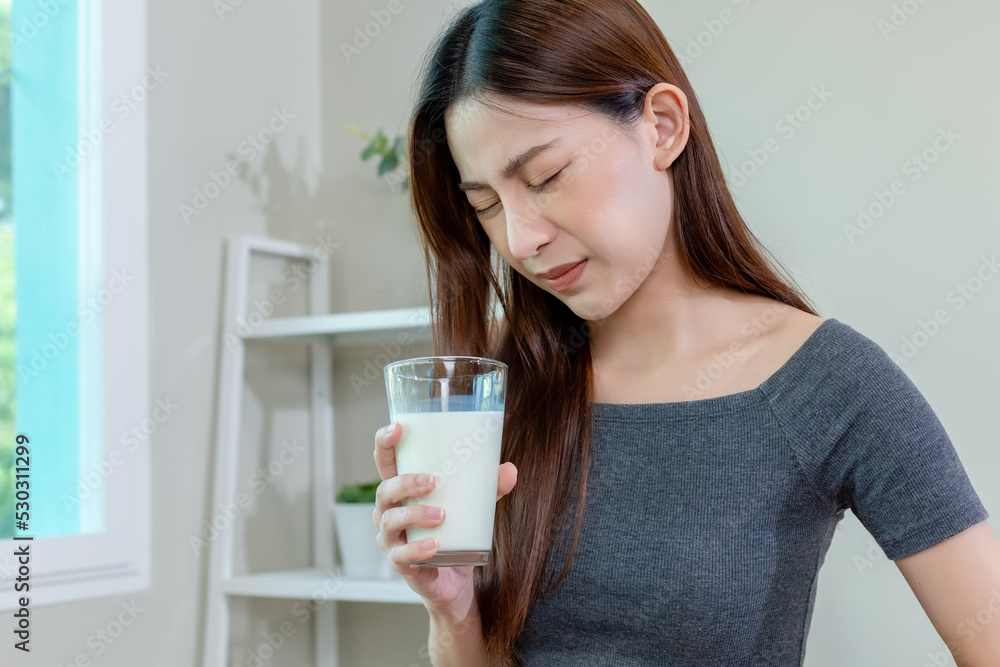 Asian female holding glass milk stomach ache after drinking milk