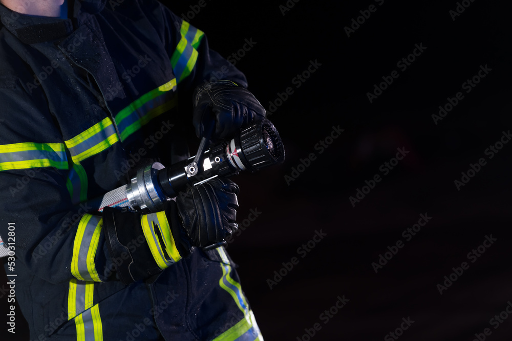Firefighters use a water hose to eliminate a fire hazard. Team of firemen in the dangerous rescue mission. Firefighters use a water hose to eliminate a fire hazard. Team of firemen in the dangerous rescue mission.