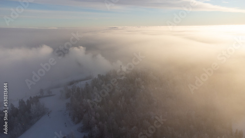 Sunrise breaking through the thick white fog at the top of Vuokatti Hill, a ski resort in Vuokatti, Finland. The Scandinavian experience of winter. Morning fog lingers over the Finnish tundra photo