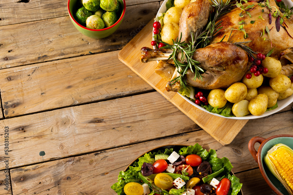 Fototapeta premium Overhead view of thanksgiving table roast turkey, vegetables and copy space on wood