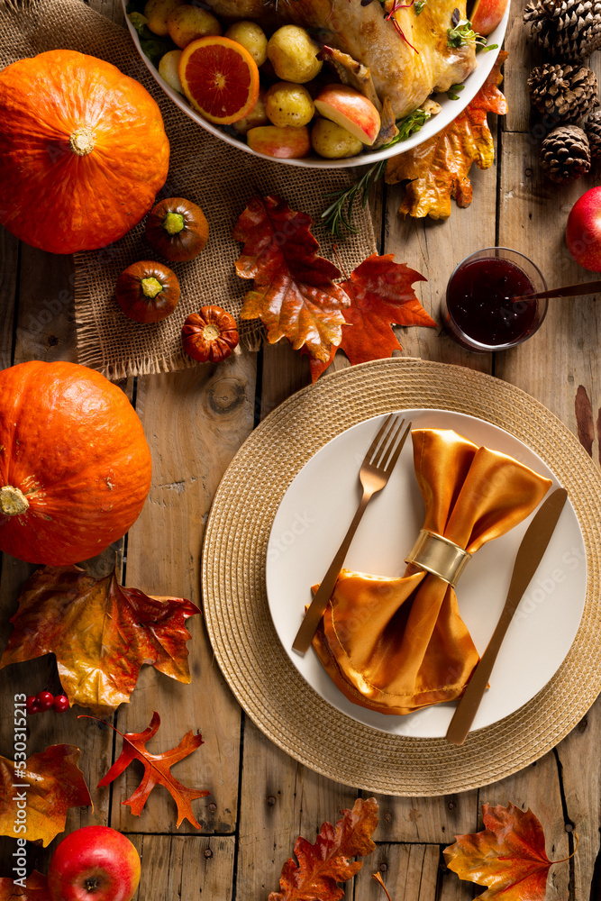 Fototapeta premium Overhead view of thanksgiving roast turkey with potatoes and autumn decoration on wood