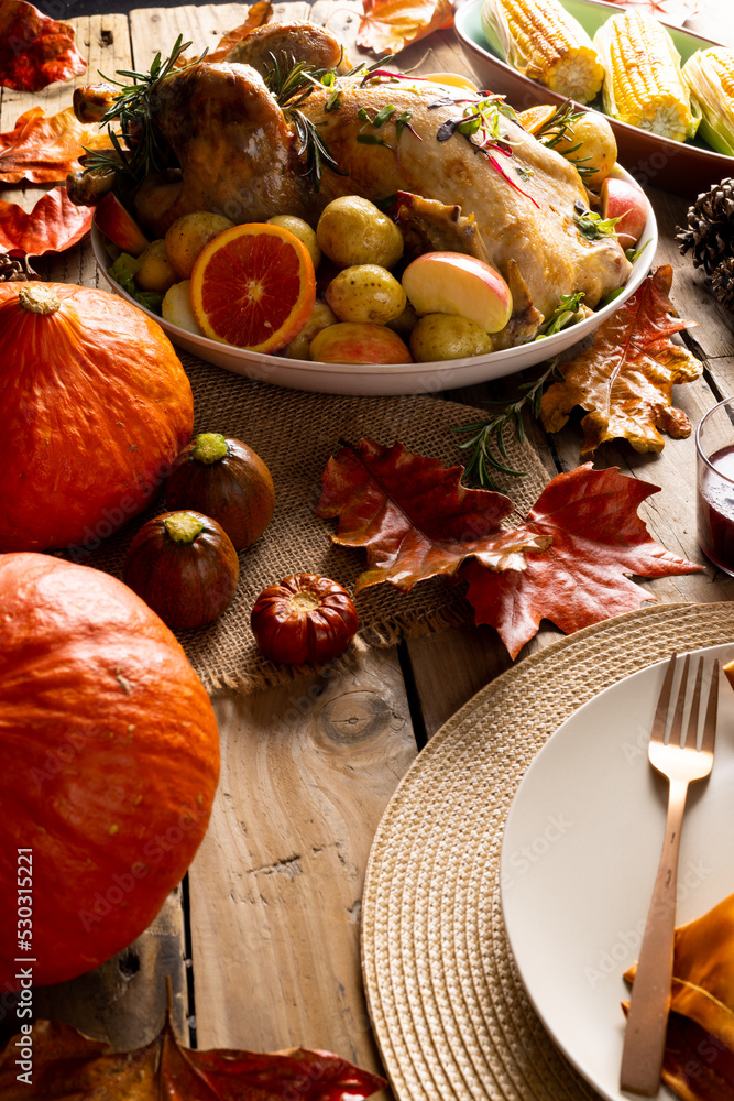 Fototapeta premium Overhead view of thanksgiving roast turkey with potatoes and autumn decoration on wood
