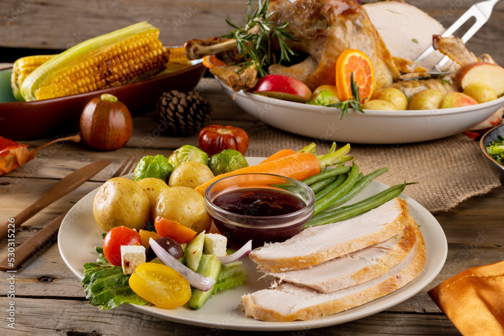 Fototapeta premium Overhead view of thanksgiving plate of roast turkey with vegetables on wooden background
