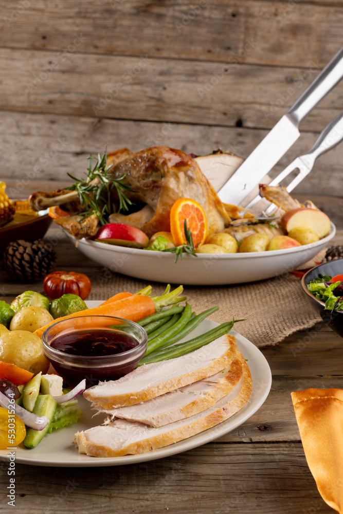 Fototapeta premium Overhead view of thanksgiving roast turkey with vegetables and copy space on wooden background