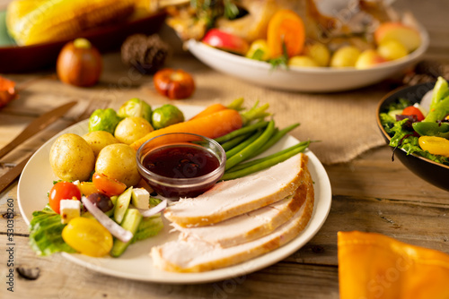 Overhead view of plate of thanksgiving roast turkey with vegetables on wooden background