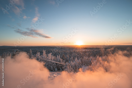 Breathtakingly frosty morning at a viewpoint in Rovaniemi, a Finnish city on the Arctic Circle. A view of the snowy landscape at golden hour. Snow-covered untouched forest