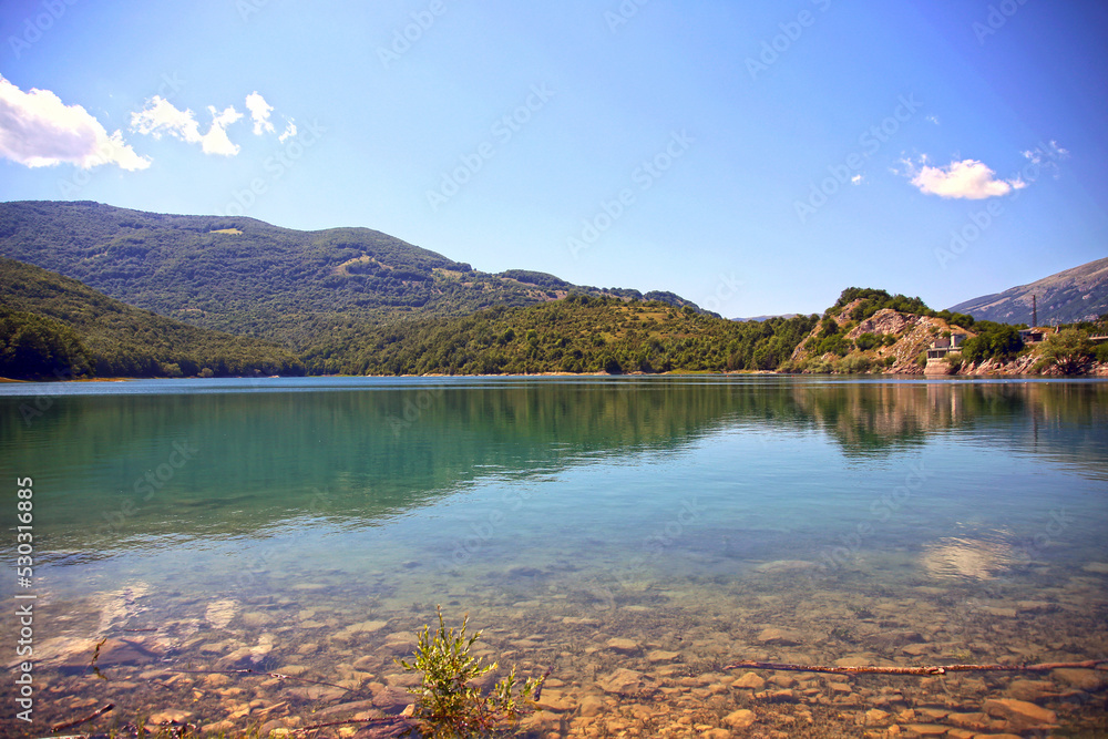 Waterfront of the Lago Della Montagna Spaccata, surrounded by green tree-lined mountains, Alfedena, Abruzzo, Italy