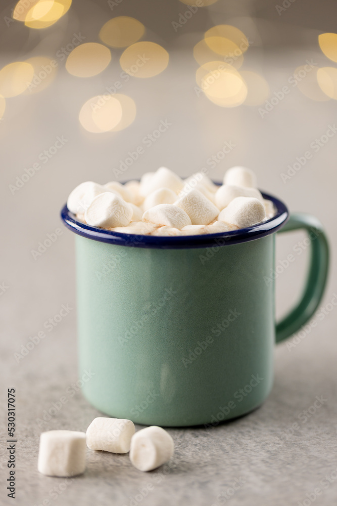 Image of green mug with christmas marshmallows with copy space and fairy lights in background Image of green mug with christmas marshmallows with copy space and fairy lights in background