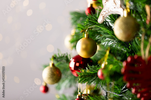 Image of christmas tree with baubles decoration and copy space on grey background