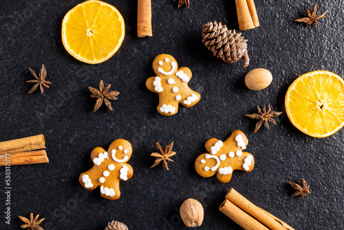 Image of gingerbread man cinnamon sticks and christmas decoration on black