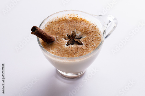 Image of glass of christmas milk with cinnamon stick, anise star and copy space on white background
