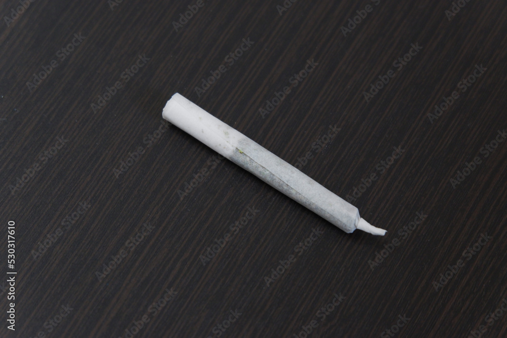 Marijuana or Cannabis Joints. Close-up of a rolled hashish joint (cigarette with hash or marijuana) on a black table background. Weed and Ganja-joint cigarette.close-up Marijuana or Cannabis Joints. Close-up of a rolled hashish joint (cigarette with hash or marijuana) on a black table background. Weed and Ganja-joint cigarette.close-up