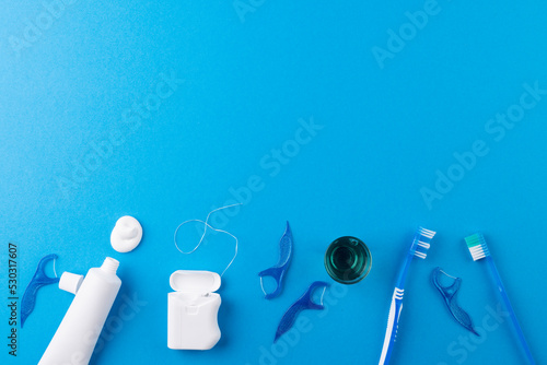 Image of toothbrush, toothpaste, string and liquid on blue surface