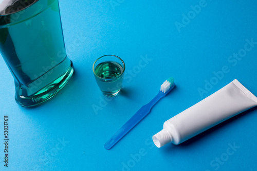 Image of cleaning liquid, toothbrush and toothpaste on blue surface