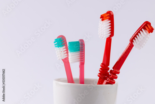 Image of toothbrushes in cup on grey background