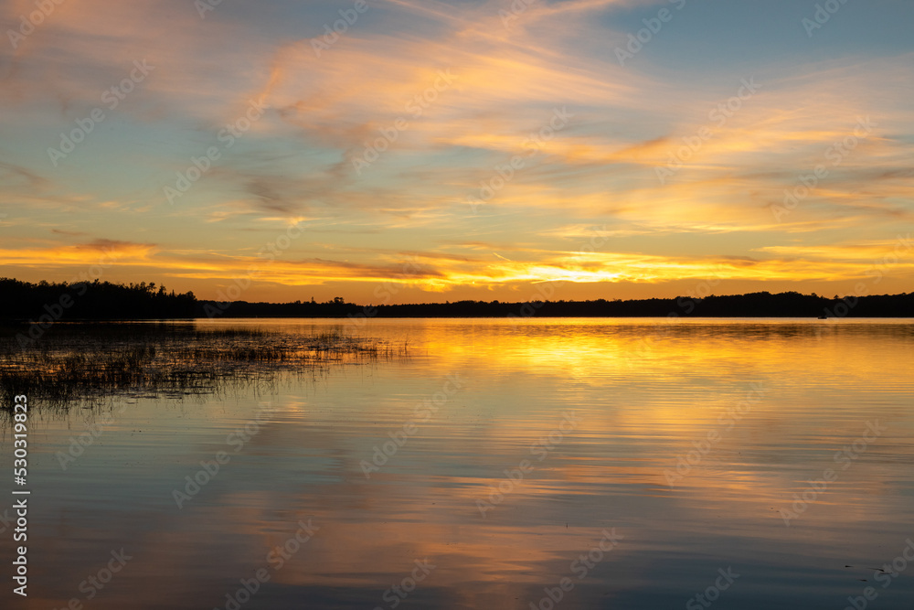 Beautiful sunsets in northern fishing lake illustrate tremendous color and light patterns from the sun and clouds to define beauty in nature through stunning display