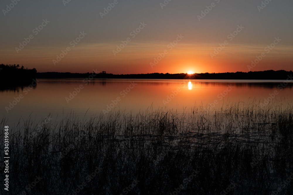 Beautiful sunset on northern lake with reflection