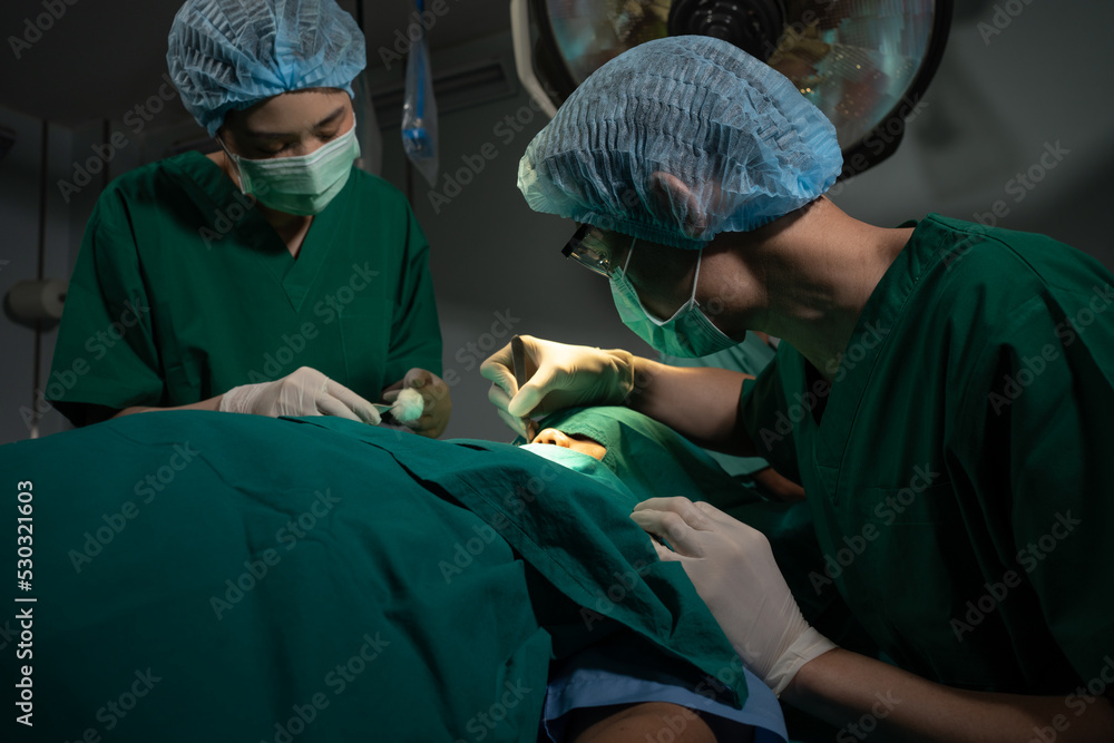 Asian Professional surgeons team performing surgery in the operating room, surgeon, Assistants, and Nurses Performing Surgery on a Patient, health care cancer and disease treatment concept Asian Professional surgeons team performing surgery in the operating room, surgeon, Assistants, and Nurses Performing Surgery on a Patient, health care cancer and disease treatment concept